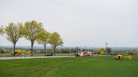 Mehrere Rettungswägen und zwei Hubschrauber stehen an einer Straße bei Albig im Kreis Alzey-Worms.