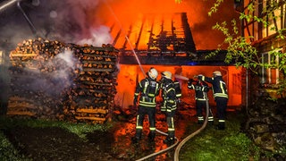 Die Scheune steht in Flammen, Feuerwehrleute versuchen den Brand in Heimweiler