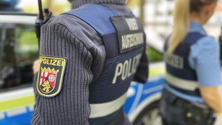 Zwei Polizistinnen stehen in Uniform vor einem Einsatzfahrzeug (Symbolfoto).