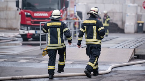 Zwei Feuerwehrleute am Einsatzort bei einem Brand am Wertstoffhof in Welgesheim