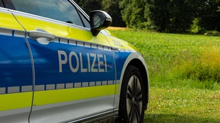 Ein Polizeiauto steht auf einem Feld.