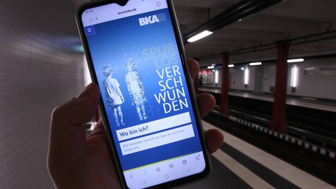 Ein Handy zeigt eine Suchmeldung nach vermissten Kindern.
