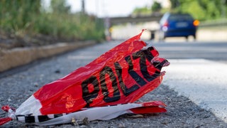 Reste eines Absperrbandes der Polizei liegen auf der Straße (Symbolbild).