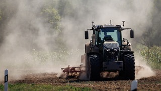 Symbolbild: Ein Landwirt bearbeitet mit seinem Traktor ein abgeerntetes Getreidefeld.
