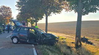 Eine Frau ist bei Biebelnheim mit ihrem Pkw frontal gegen einen Baum geprallt. Der vordere Teil des Wagens ist komplett zerstört.