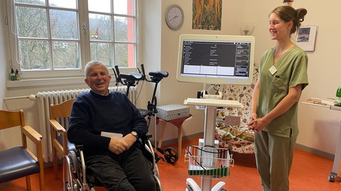 Pflegefachraft Nelli Kern mit dem Telepflegegerät "Carlo" und Bewohner Walter Wagner. Über die Telepflege ist es möglich eine Pflegefachkraft zu kontaktieren und direkt mit ihr über den Bildschirm zu kommunzieren.