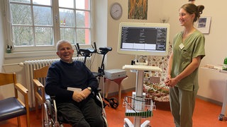 Pflegefachraft Nelli Kern mit dem Telepflegegerät "Carlo" und Bewohner Walter Wagner. Über die Telepflege ist es möglich eine Pflegefachkraft zu kontaktieren und direkt mit ihr über den Bildschirm zu kommunzieren.