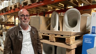 Ein Mann steht vor einem Regal mit Toilettenschüsseln: Die Zander-Gruppe hat die insolvente Firma Laeis Sanitär aus Trier übernommen.
