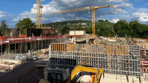 Der Rohbau auf der Baustelle an der Südallee mit zwei Baustellenkränen, im Hintergrund der Petrisberg