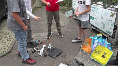 Die Schüler stehen vor dem Sammelbehälter und zählen die gesammelten Elektrogeräte.