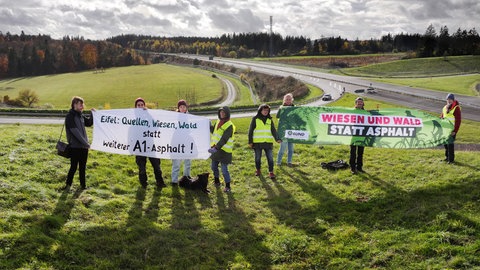 Umweltschützer haben sich bei einer Protestaktion an der A1 versammelt.