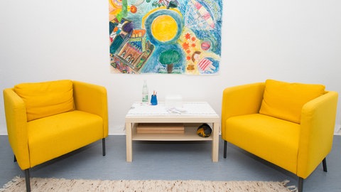 Ein Behandlungszimmer in einer psychotherapeutischen Praxis mit zwei gelben Sesseln.