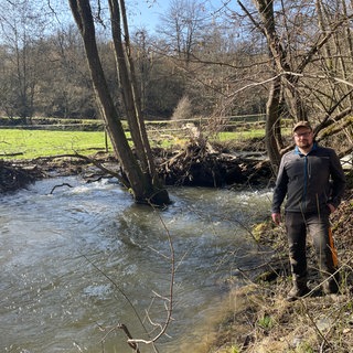 Am Fischbach bei Herrstein hat das Totholz eine Art natürlichen Staudamm geschaffen. Landwirt Tobias Brunk wünscht sich, dass er beseitigt wird.