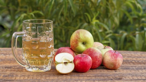 Glasbecher mit Apfelwein und geernteten Äpfeln. Im Jahr 2024 ist der Viez ist in die Liste des immateriellen Kulturerbes der UNESCO aufgenommen worden