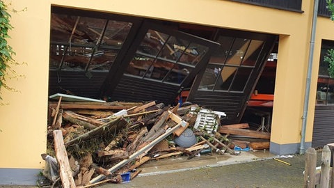 Ein Blick auf die Eingangstore der Lagerhalle zeigt: Das Hochwasser hat im Betrieb in Schönecken in der Eifel ein Chaos hinterlassen. 