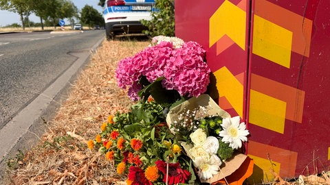 Blumen liegen an der Stelle, wo am Mittwoch ein Student bei einem Messerangriff auf offener Straße in Trier getötet worden ist.