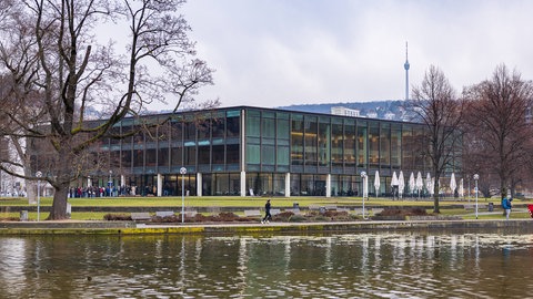 Weitwinkelaufnahme des Landtags von Baden-Württemberg in Stuttgart kurz vor der Landtagswahl 2026 mit Blick über den Eckensee. Vor dem Gebäude sind Menschen zu sehen, im Hintergrund der Stuttgarter Fernsehturm. (Symbolbild)