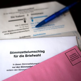 Weißer Stimmzettelumschlag für die Briefwahl zur Bundestagswahl 2025 und roter Wahlbriefumschlag