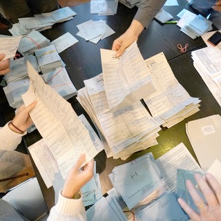 Stimmzettel bei einer Wahl werden von Wahlhelfern ausgezählt