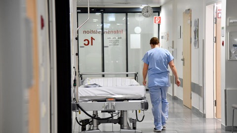 Ein Mitarbeiter im Gesundheitswesen geht auf einer Intensivstation den Flur entlang. 