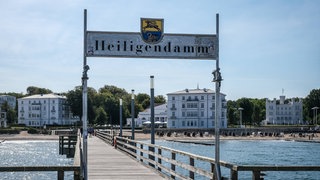 Seebrücke am Seebad Heiligendamm mit Blick auf das Grand Hotel Heiligendamm und weitere Luxusimmobilien im Hintergrund.