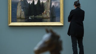 Eine Frau betrachtet in Berlin das Bild "Die Toteninsel" (1883) von Arnold Böcklin. 