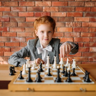 Ein Mädchen mit roten Haaren spielt Schach: Mit der Netflix-Serie „Damengambit“ wurde Schach populärer. Wer Schach spielt, gilt als schlau. Doch steigert es wirklich die Intelligenz? Was lässt sich dabei fürs Leben lernen?