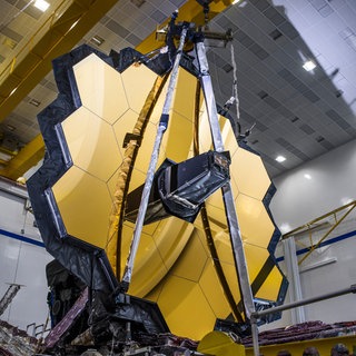James-Webb-Weltraumteleskop nach einem erfolgreichen Entfaltungstest seines Hauptspiegels in der gleichen Konfiguration, die es im Weltraum haben wird. Die Weltraumbehörden Europas, der USA und Kanadas wollen mit dem neuen Teleskop mehr über das frühe Universum lernen. Mit dem Teleskop sollen die ersten nach dem Urknall entstandenen Galaxien beobachtet werden.