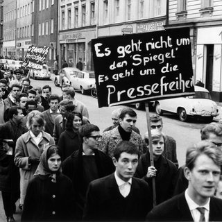 Auf dem Plakat einer Gruppe von Demonstranten steht: "Es geht nicht um den "Spiegel". Es geht um die Pressefreiheit" – In München demonstrierten am 2.11.1962 Studenten gegen die jüngsten Polizei-Maßnahmen in der Hamburger "Spiegel"-Redaktion. Etwa 300 Teilnehmer maschierten mit Spruchtafeln von der Universität zum Königsplatz, wo ein Sprecher die Forderung der Studenten nach Pressefreiheit unterstrich. Im Zuge der "Spiegel"-Affäre mussten sich Mitarbeiter des Nachrichtenmagazins "Spiegel" wegen eines kritischen Artikels gegen eine Anklage des Landesverrats zur Wehr setzen.
