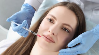 Junge Frau bekommt Injektion von Botox in ihre Lippen: Immer mehr junge Frauen lassen ihre Lippen aufpolstern, erste Fältchen straffen oder sich Implantate in den Po setzen. 