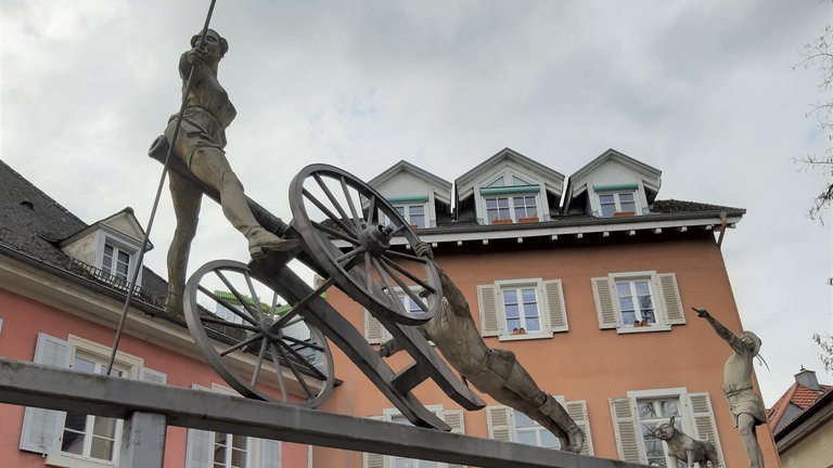 Badische Revolution 1848: Als "Feldherr" ist Friedrich Hecker ungeübt: Als Truppen des Deutschen Bundes ihm in Donaueschingen den Weg in den Norden versperren, muss er Richtung Südwesten abbiegen und gelangt ins Städtchen Schopfheim im Wiesental, wo er eine seiner feurigen Reden hält. Doch er überschätzt sein Charisma. Nur zwei Einheimische und ein Hund schließen sich seinen etwa 800 Mann an. – Auf dem Marktplatz in Schopfheim steht ein Denkmal. Vorne auf der Kanone ist Emma Herwegh zu sehen, hinten der Hund.