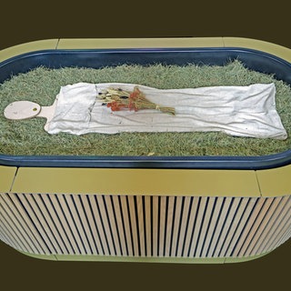 Heu, Stroh, Blumen und eine Holzfigur liegen in einem sogenannten „Kokon“ bei einem Pressegespräch zu der neuen Bestattungsform "Reerdigung" in der Kapelle auf dem Parkfriedhof Eichhof. Der Anbieter „Meine Erde“ bietet die neuen Bestattungsform an. Ein Leichnam wird auf Heu, Stroh und Grünschnitt gebettet, innerhalb von 40 Tagen wird er zu Erde.