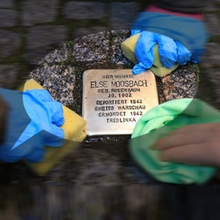 Drei Kinderhände putzen einen Stolperstein in der Lübecker Straße in Magdeburg: Seit Jahrzehnten behandeln Schulen den Holocaust im Unterricht. Trotzdem ist "Jude" auf Schulhöfen als Schimpfwort zu hören und Jugendliche provozieren mit Wörtern wie "vergasen". Viele Lehrkräfte fühlen sich in solchen Situationen überfordert. 