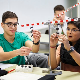 Schüler in einer Schulklasse experimentieren in Physik zum Thema Hebelwirkung