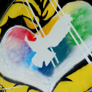 Graffiti mit weißer Friedenstaube in einem farbigen Herzen: Während der Friedensbewegung der 1980er- und 1990er-Jahre galt der Pazifismus als respektable politisch-ethische Haltung. Das hat sich mit dem russischen Angriffskrieg gegen die Ukraine geändert. 