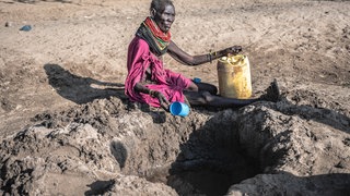 Eine Turkana versucht, in Kakuma (nordwestliches Turkana County in Kenia) versickertes Grundwasser aus einem ausgetrockneten Flussbett zu schöpfen: Weltweit ziehen rund 100 Millionen Nomaden durch meist karge Regionen in Afrika und Asien. Der Klimawandel erschwert die Suche nach Wasser und Weideland. 