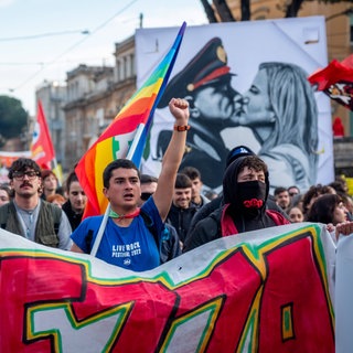 Tausende Menschen demonstrieren am 14. Dezember 2024 in Rom gegen das Gesetz 1660, das das Demonstrationsrecht einschränken soll und u.a. härtere Strafen für Demonstrationen und Straßenblockaden vorsieht. Ein Plakat der Demonstranten zeigt einen Kuss zwischen dem faschistischen "Duce" Benito Mussolini und Italiens Regierungschefin Giorgia Meloni.