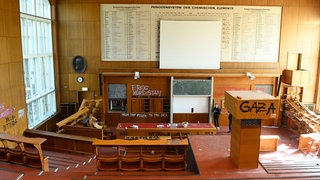 Nach einer Besetzung des Emil-Fischer-Saals der Humboldt-Universität in Berlin im April 2025 durch propalästinensische Aktivisten, die durch die Polizei geräumt wurde, sind so umfangreiche Schäden entstanden, dass der Raum nicht mehr nutzbar ist: Seit dem Terrorangriff der Hamas am 7. Oktober 2023 und der Militäroffensive Israels eskalieren Proteste an den Hochschulen. Unis versuchen nun, Lernorte für selbstkritisches Zuhören und vorurteilsfreie Dialoge zu schaffen.