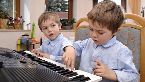 Junge Zwillinge spielen Klavier.