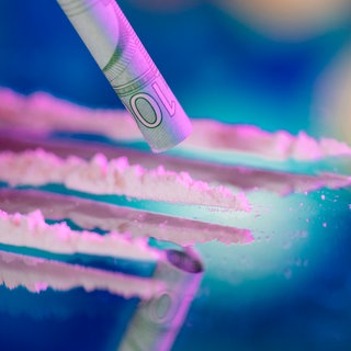 Mit einem gerollten Geldschein wird eine Linie Kokain aufgenommen: Immer mehr Menschen konsumieren Kokain, der Drogenhandel blüht. Was können Kommunen tun? Und was hilft Konsumenten? 