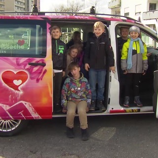 Kinder sitzen in einem neuen Herzensbus