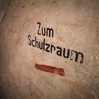 "Zum Schutzraum" steht an einer Wand im Keller eines Hauses iin Frankfurt. Durch den Angriffskrieg Russlands auf die Ukraine geraten solche Schutzräume auch in Deutschland wieder ins Bewusstsein der Bevölkerung.
