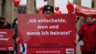 Eine Aktivistin steht vor dem Brandenburger Tor und hält ein Schild mit der Aufschrift "Ich entscheide, wen und wann ich heirate!". Terre des Femmes demonstriert mit der Aktion #meinherzgehörtmir gegen Zwangsverheiratungen und Frühehen. 