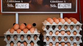 Braune Eier der Güteklasse A sowie der Gewichtsklassen XL und L an einem Marktstand. S, M oder L: Wovon hängt die Größe von Hühnereiern ab?