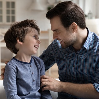 Vater mit kleinem Sohn im vertraulichen Gespräch: Sexualaufklärung ist wichtig. Altersgerechte Begriffe wie Penis oder Vulva helfen, Scham zu vermeiden und stärken den Schutz vor Missbrauch, weil Kinder Dinge klar benennen können.
