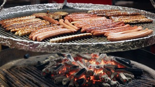 Symbolbild: Holzkohlegrill mit Würstchen auf einem Weihnachtsmarkt
