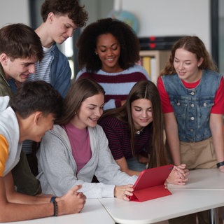 Symbolbild: Jugendliche Schüler lernen gemeinsam mit einem digitalen Tablet in einem Klassenzimmer.