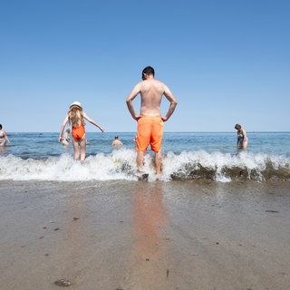 Menschen stehen im Wasser am Ostseestrand in Kühlungsborn.