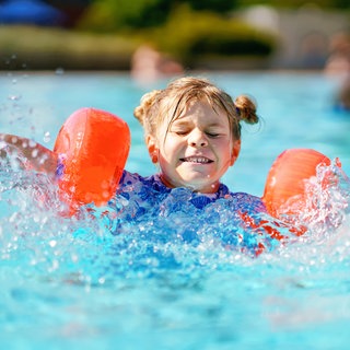 Kleines Mädchen mit Schwimmflügeln planscht im Pool: In den letzten Jahren steigt die Zahl der Grundschüler, die nicht schwimmen können. Die Gründe sind vielfältig.