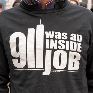 Eine Person trägt ein T-Shirt mit einer Verschwörungstheorie.